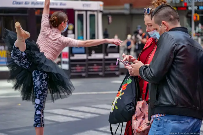 A photo of two people looking at a phone while a ballerina dances behind them